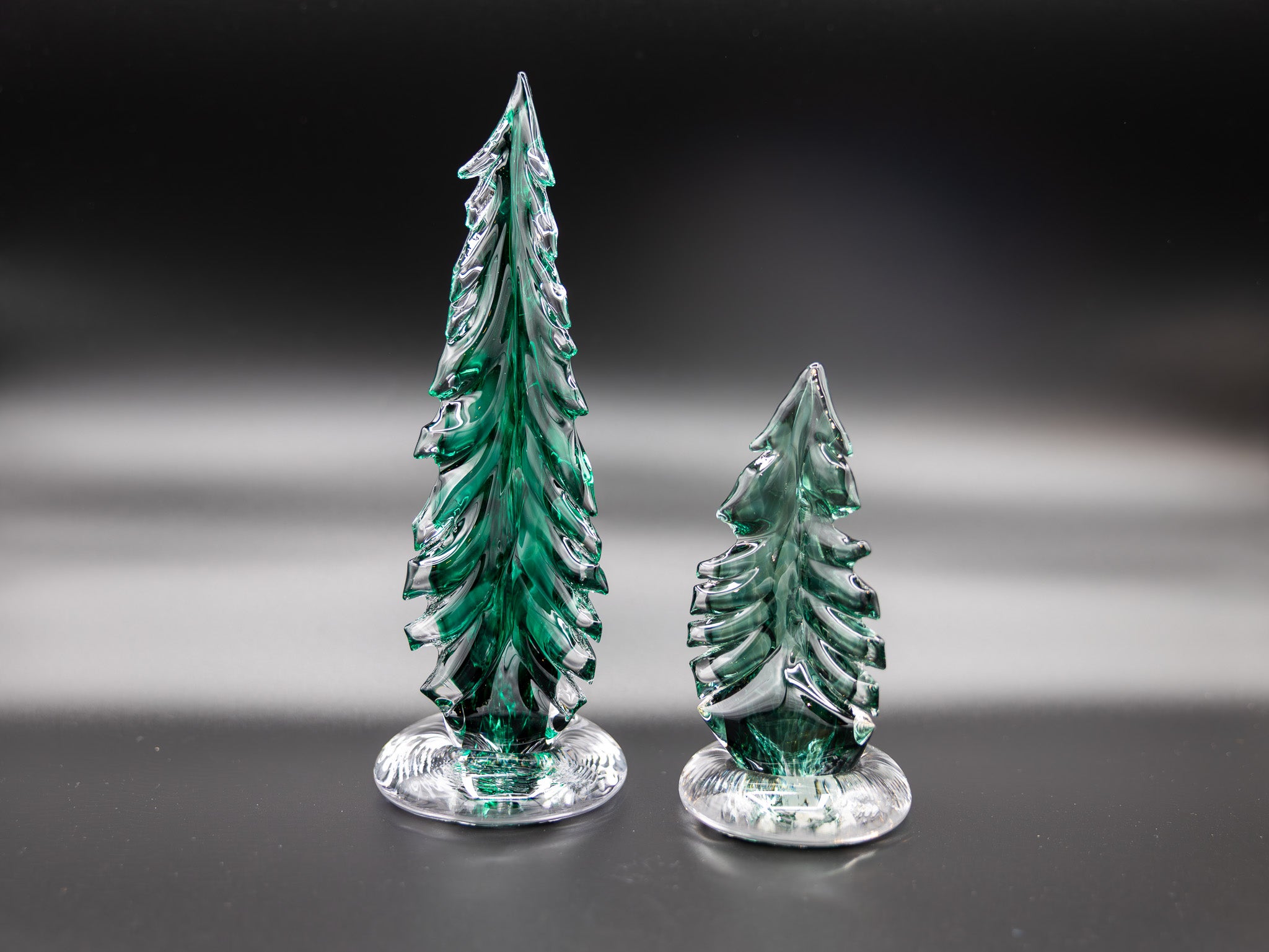 two glass trees on a dark background