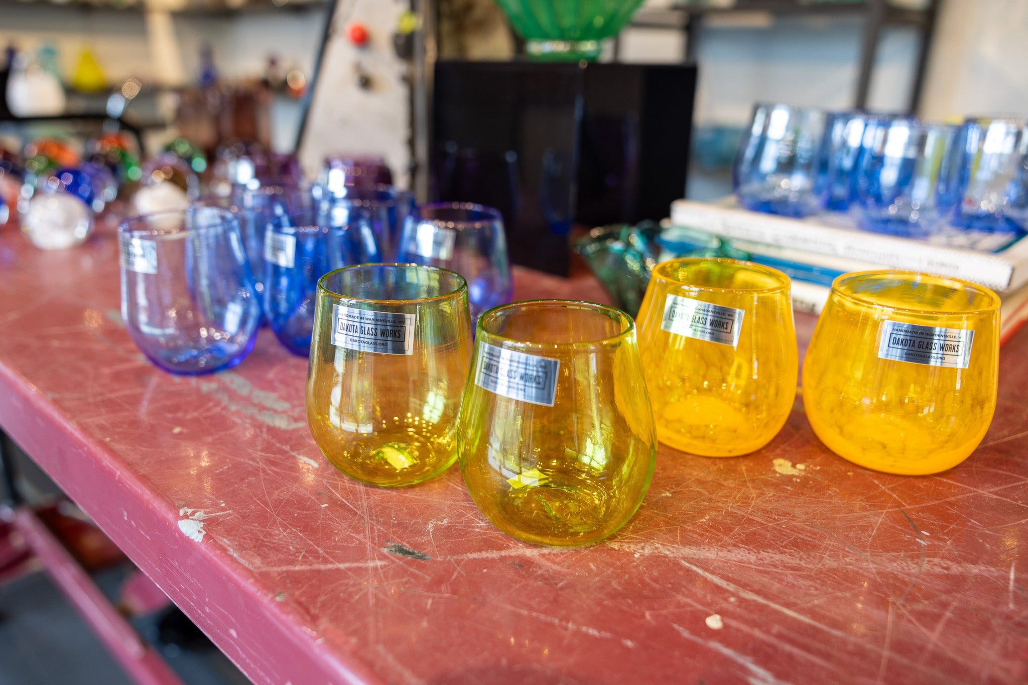 Yellow glass stemless wine glasses on a red table with blurred background