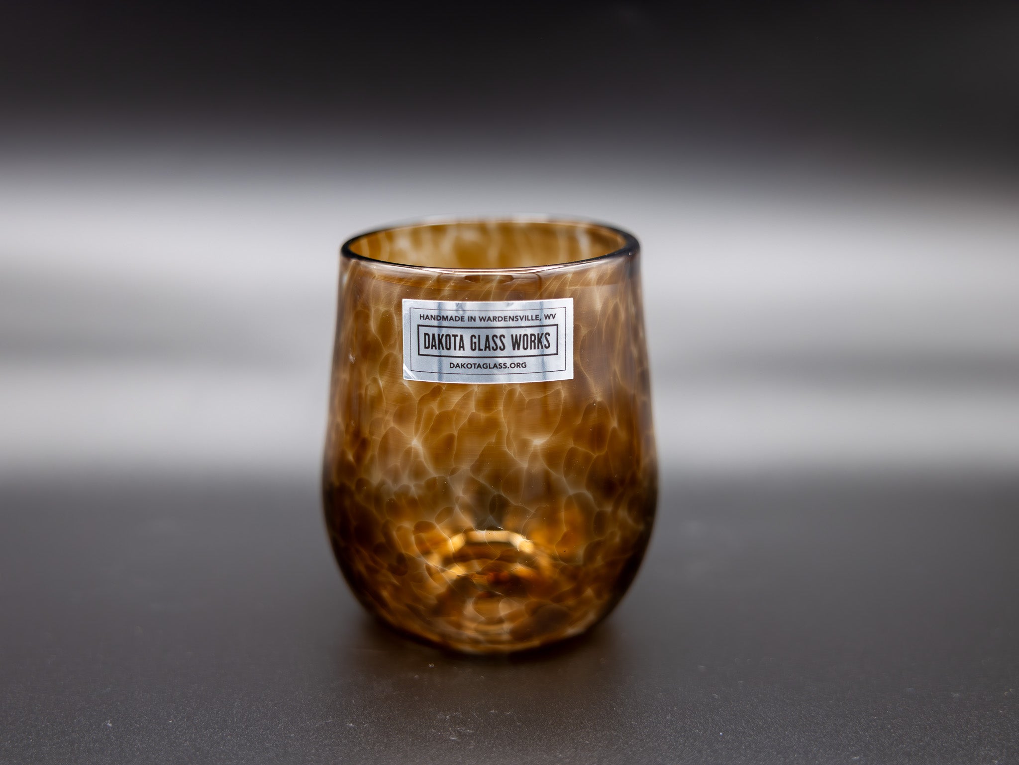 Brown stemless wine glass with a label on a dark background
