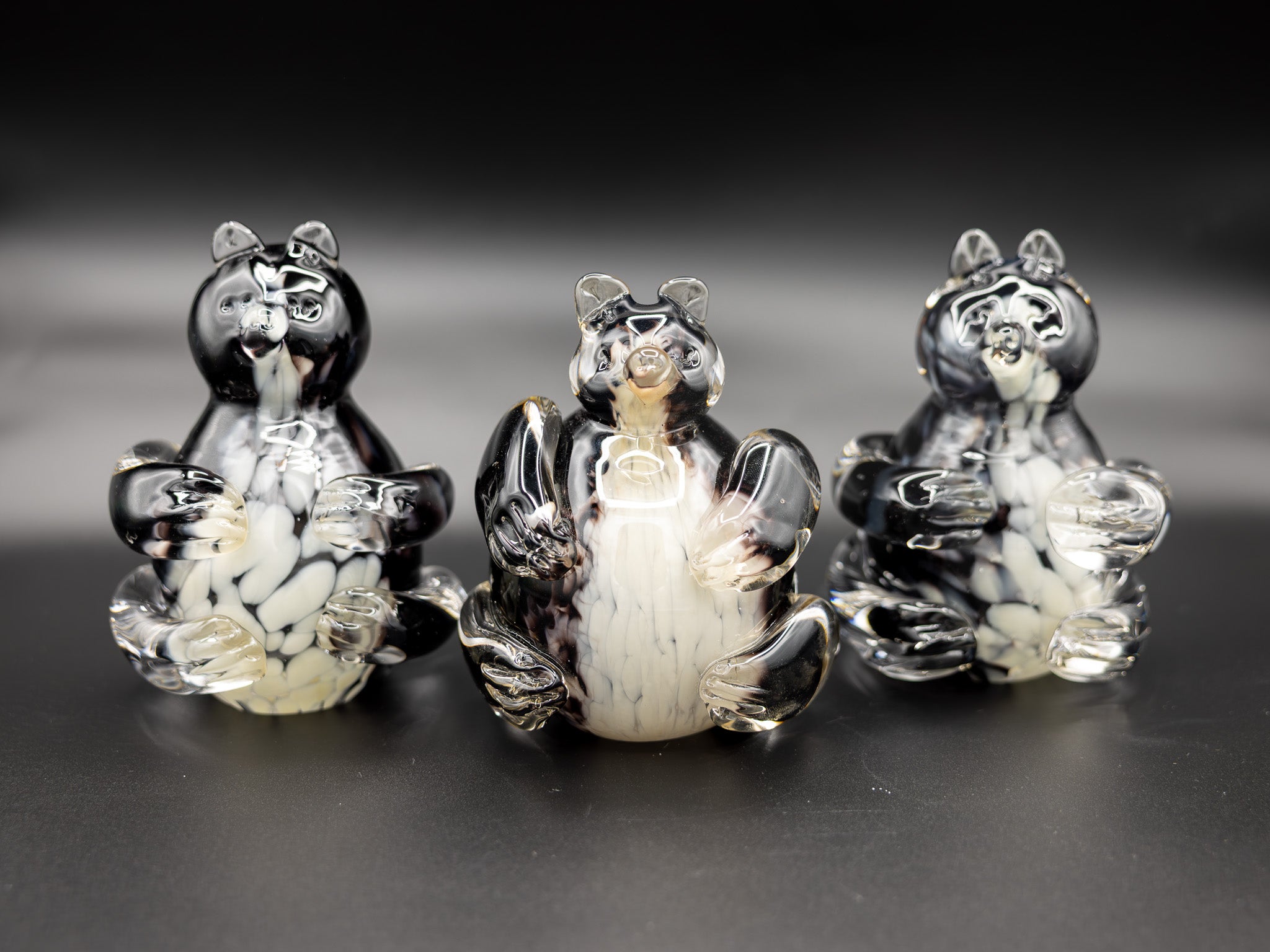 Three glass bear figurines on a reflective surface with a dark background