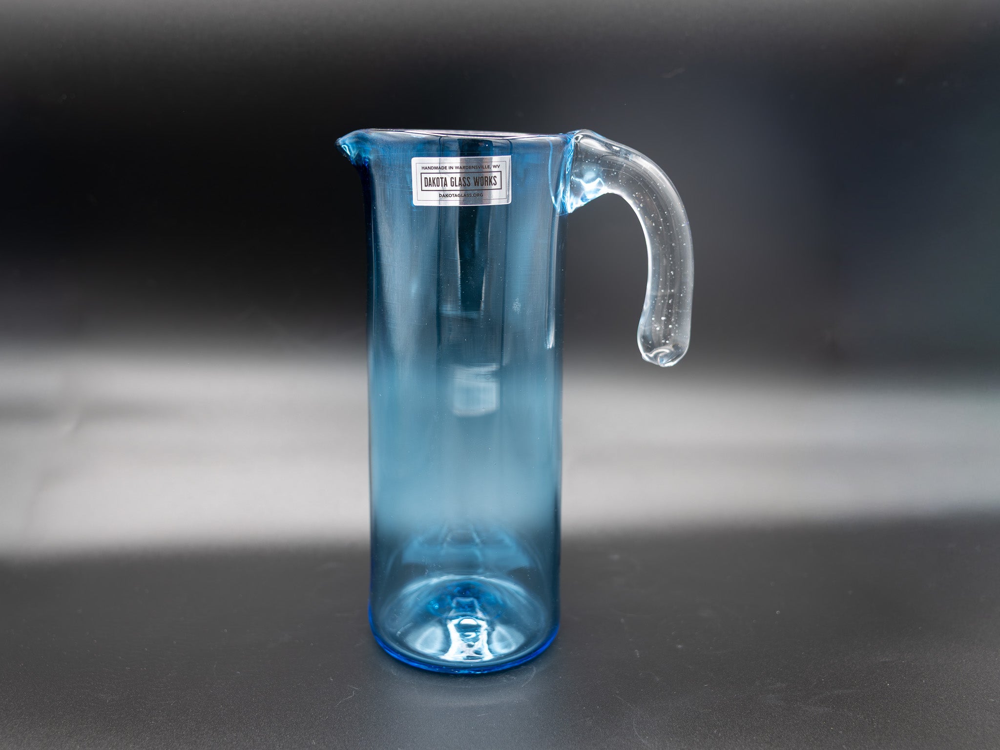 Blue glass pitcher with a handle on a dark surface