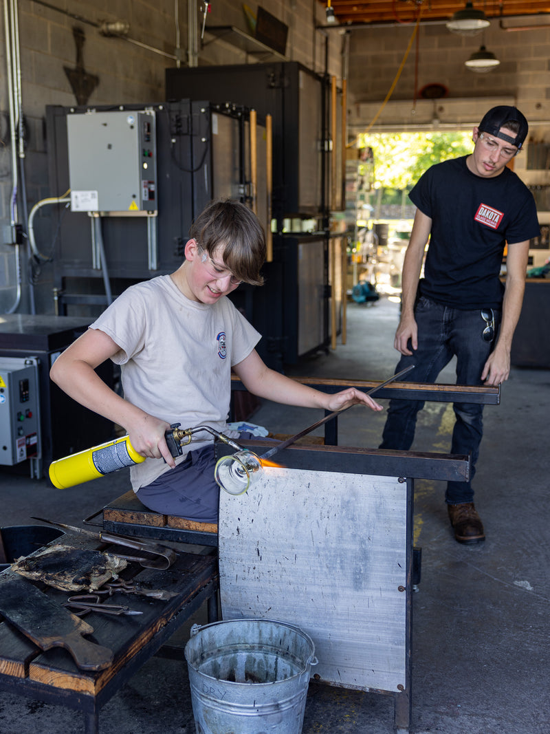 Two people working on a custom cup in the studio