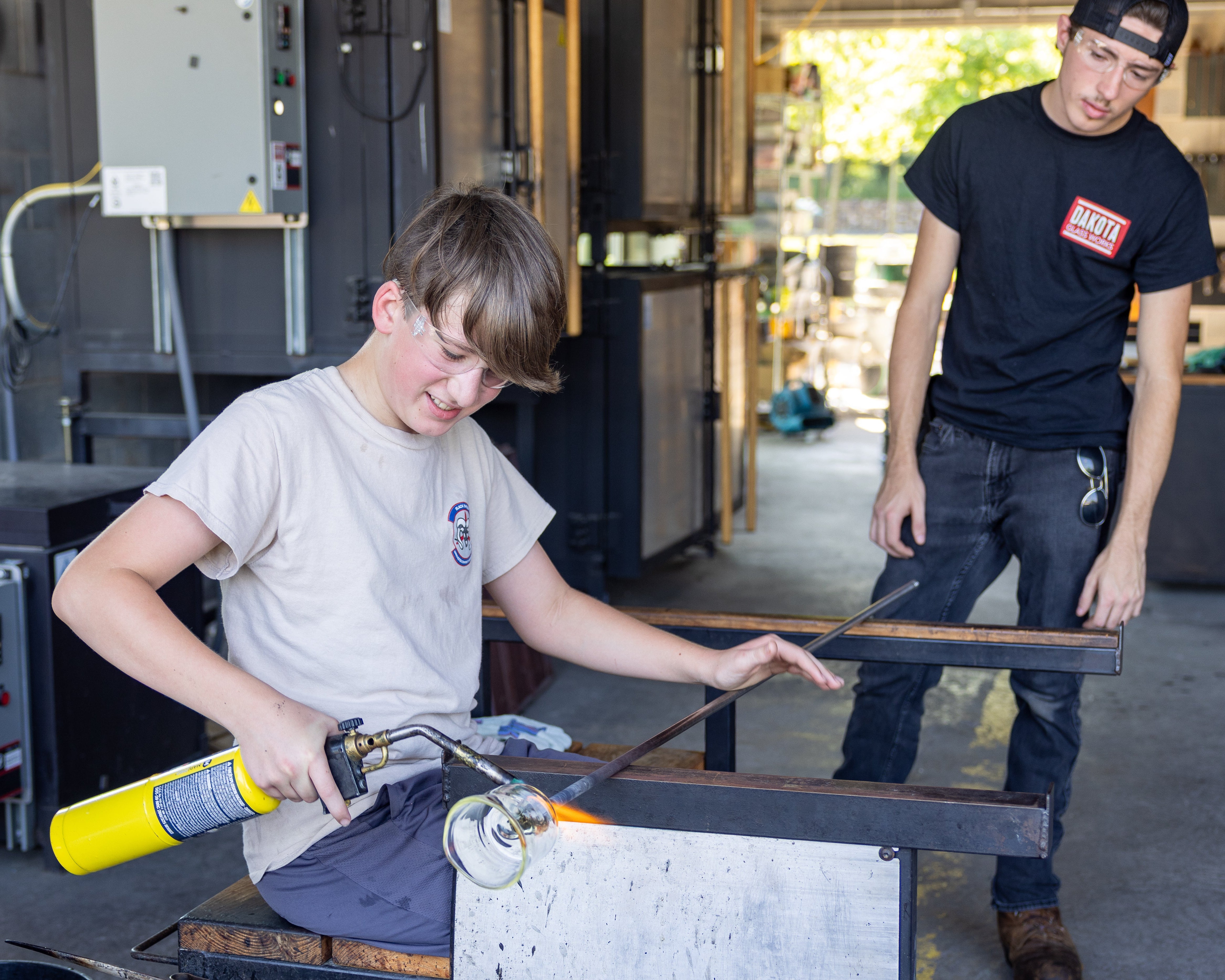 two people working on a handmade cup at the bench