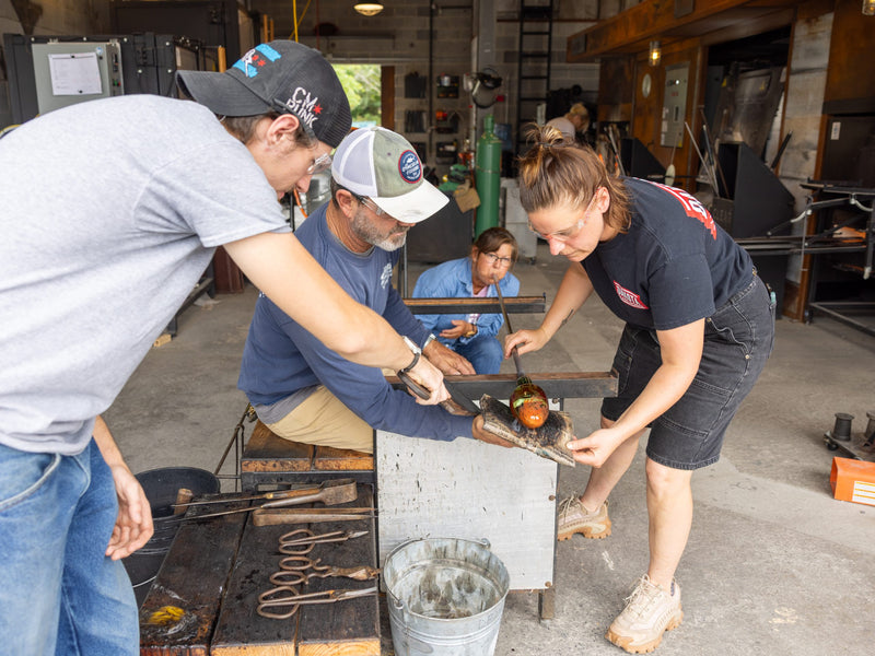 Three people working with tools in a workshop setting