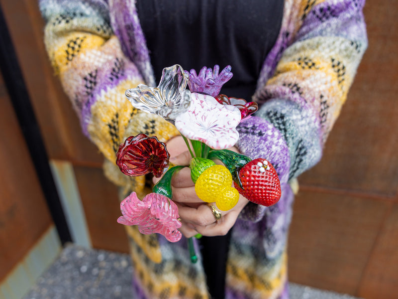 Person holding a bouquet of glass flowers and strawberries