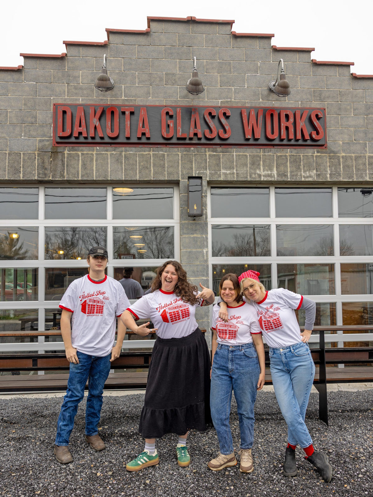 Four people posing in front of Dakota Glass Works with matching shirts.