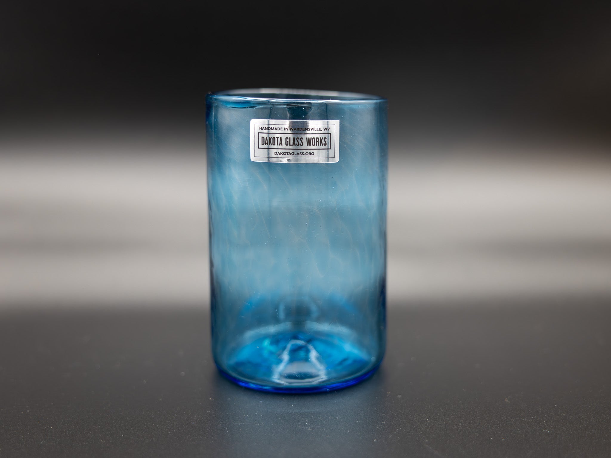 Blue glass tumbler with a label on a dark background