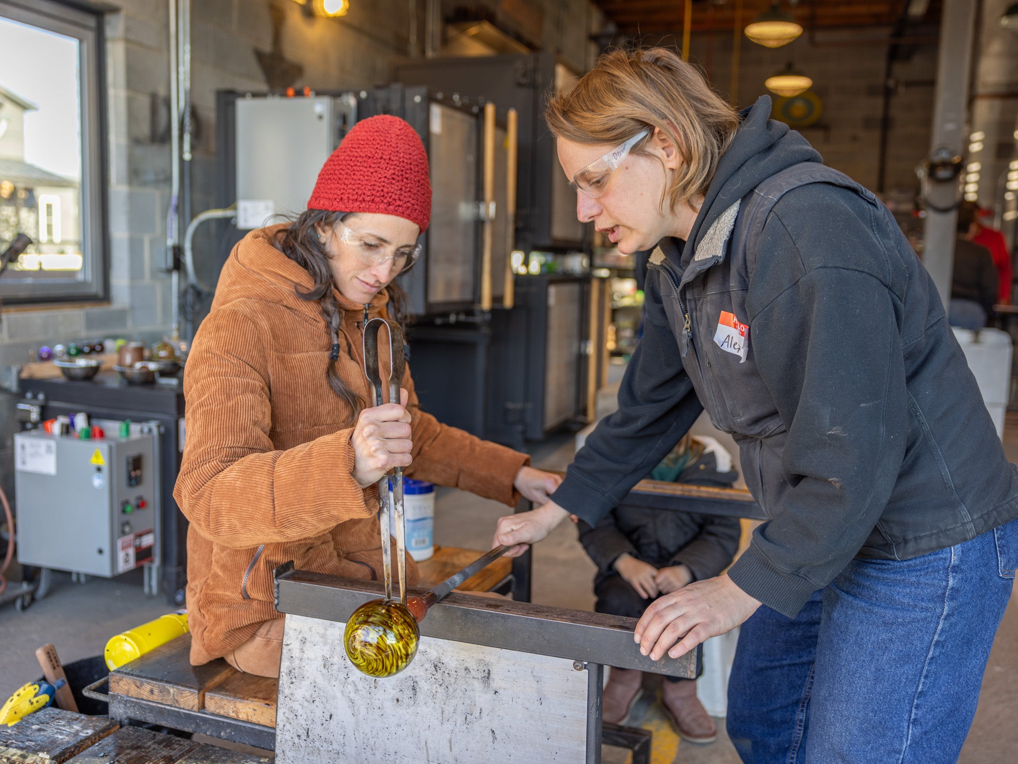 Two people working together in a glassblowing studio.