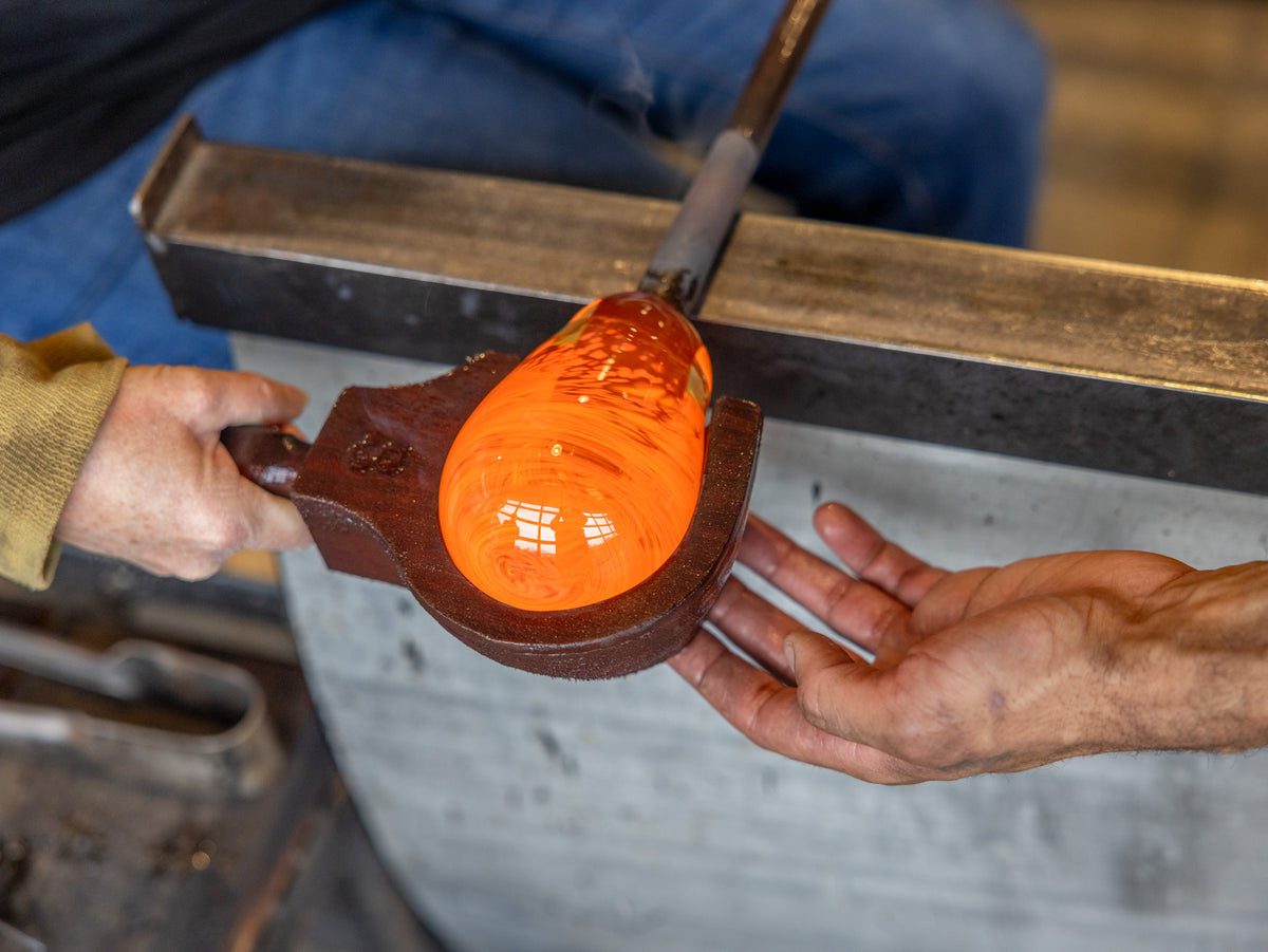 Glassblower assisting a workshop participate with blocking some glass