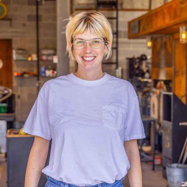 Person wearing a light purple t-shirt in a workshop setting