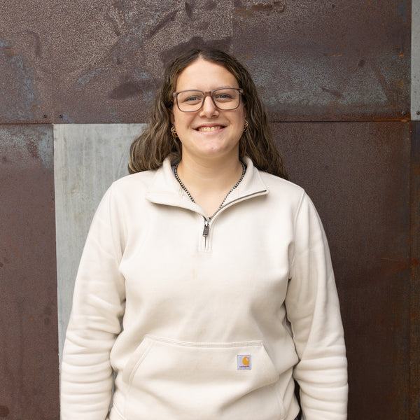 Person wearing a beige Carhartt jacket against a textured wall.