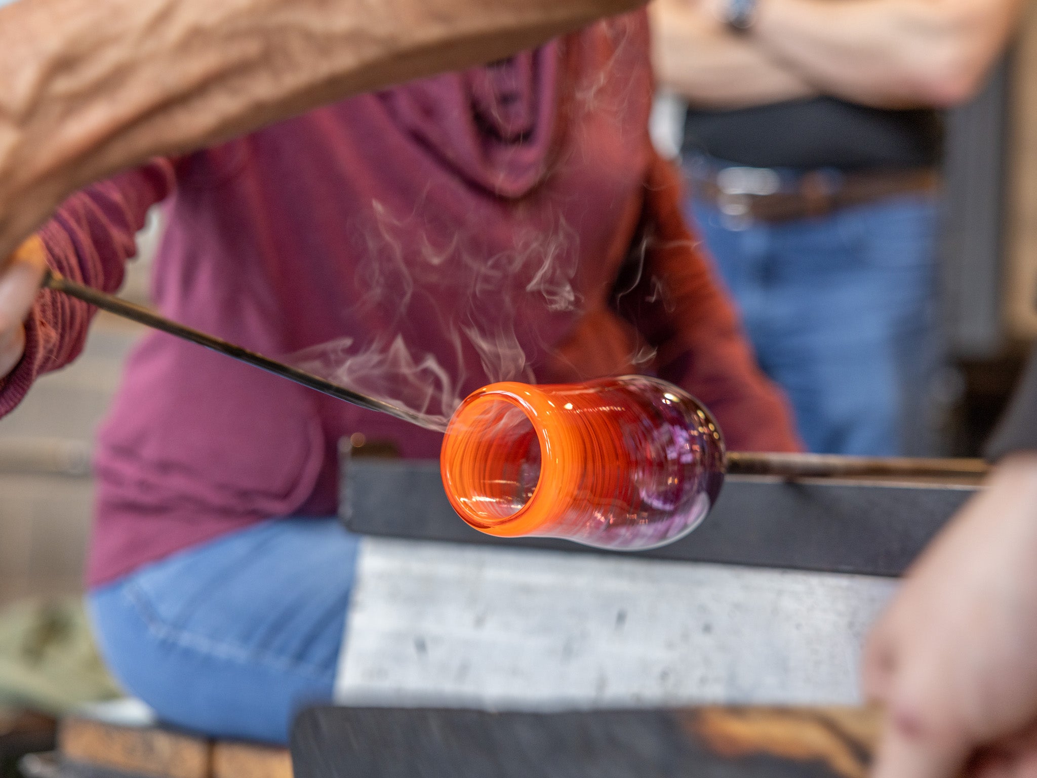 Glassblowing process with a glass object being shaped on a hot surface.